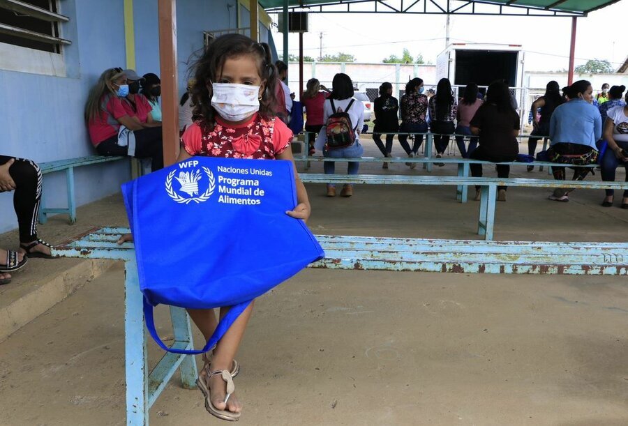 Thania, una niña de 4 años, sentada en una banca sostiene una bolsa del Programa Mundial de Alimentos (WFP)