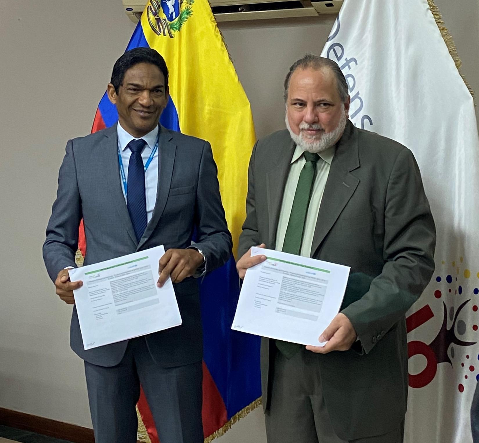 Representante de UNICEF y Defensor del Pueblo sostienen el documento del Plan de Trabajo firmado