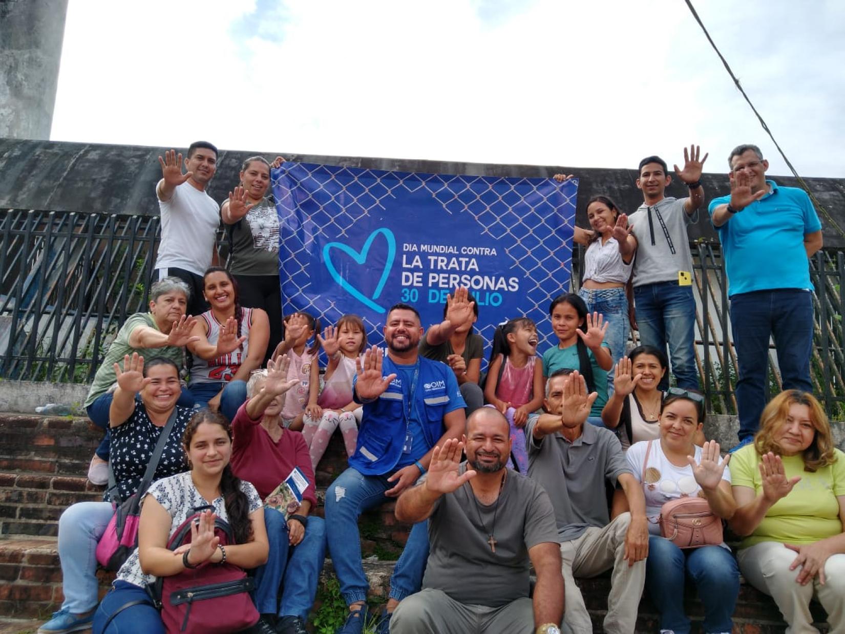 Personas sonríen frente a un banner por el Día Mundial contra la Trata de Personas.