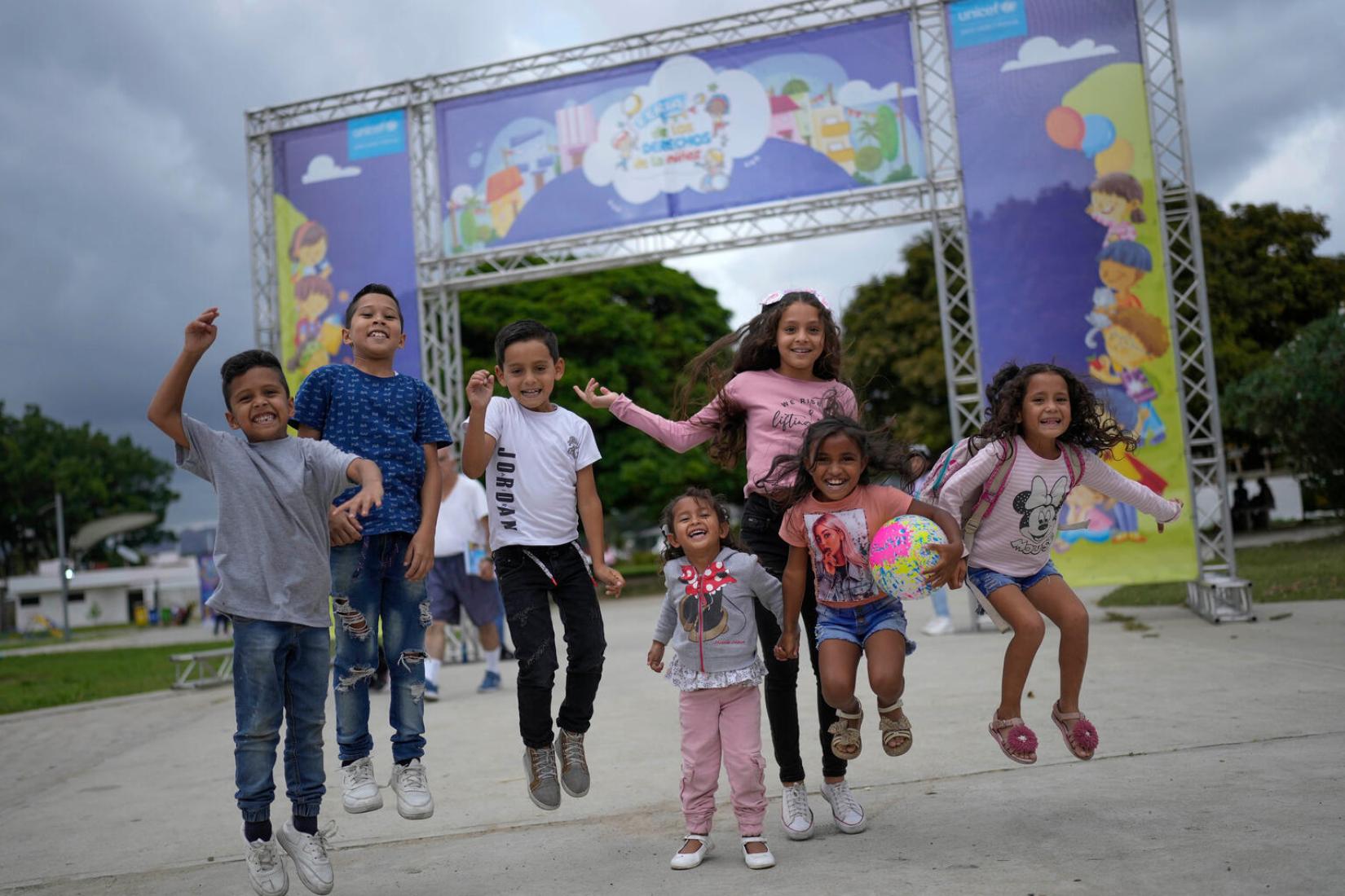 Niños y niñas saltan frente a la entrada de la Feria de los Derechos de la Niñez