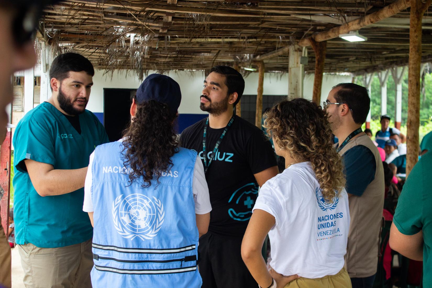 Un grupo de mujeres y hombres trabajadores humanitarios conversan.