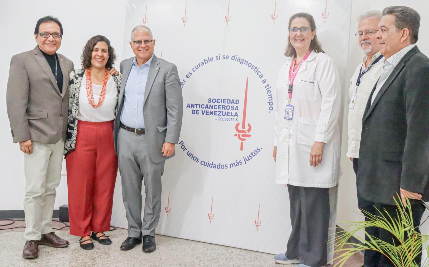 Representantes de OPS y la Clínica de Prevención del Cáncer posan frente al logo de la institución.