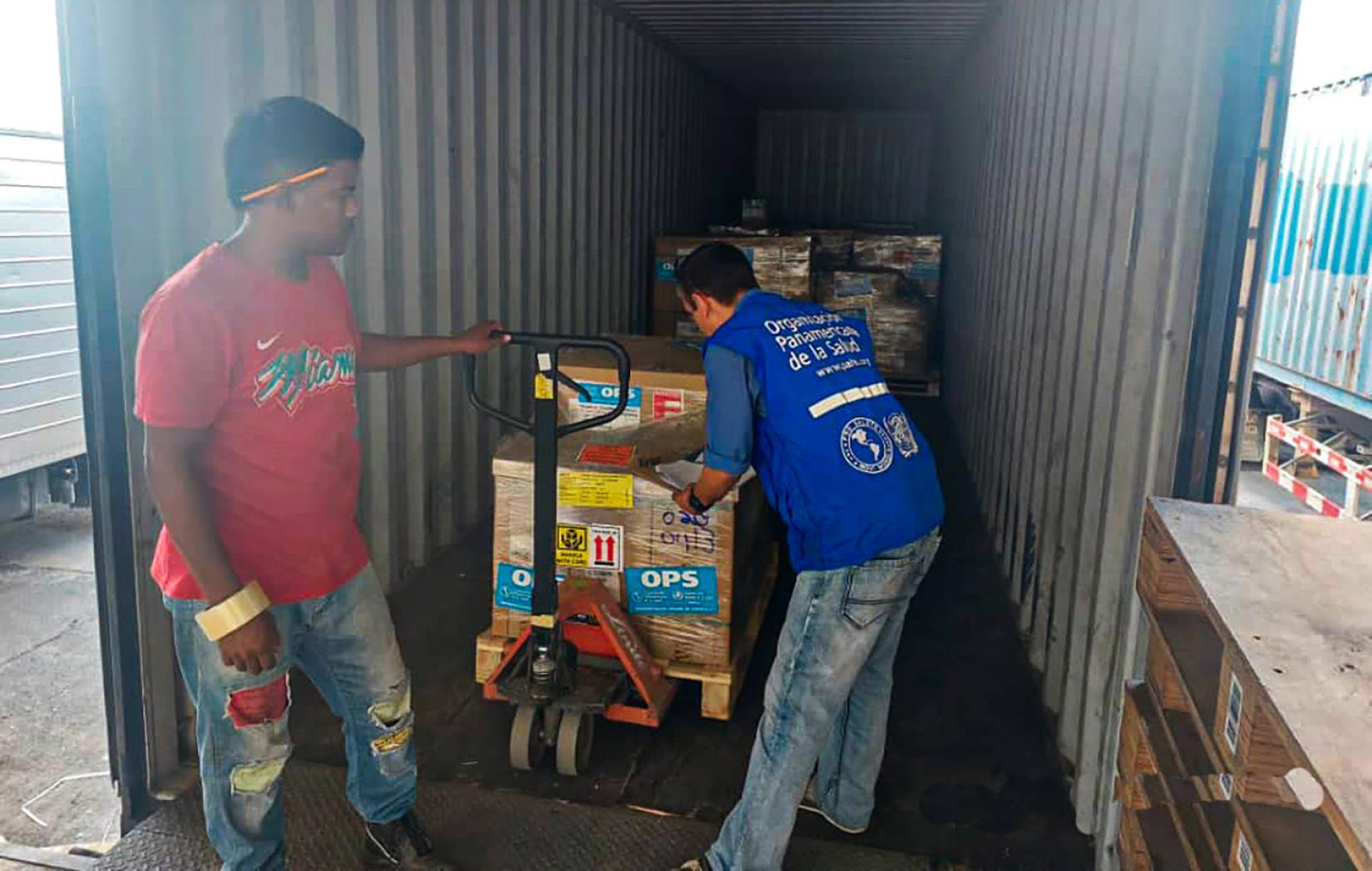 Dos hombres descargan cajas de medicamentos.