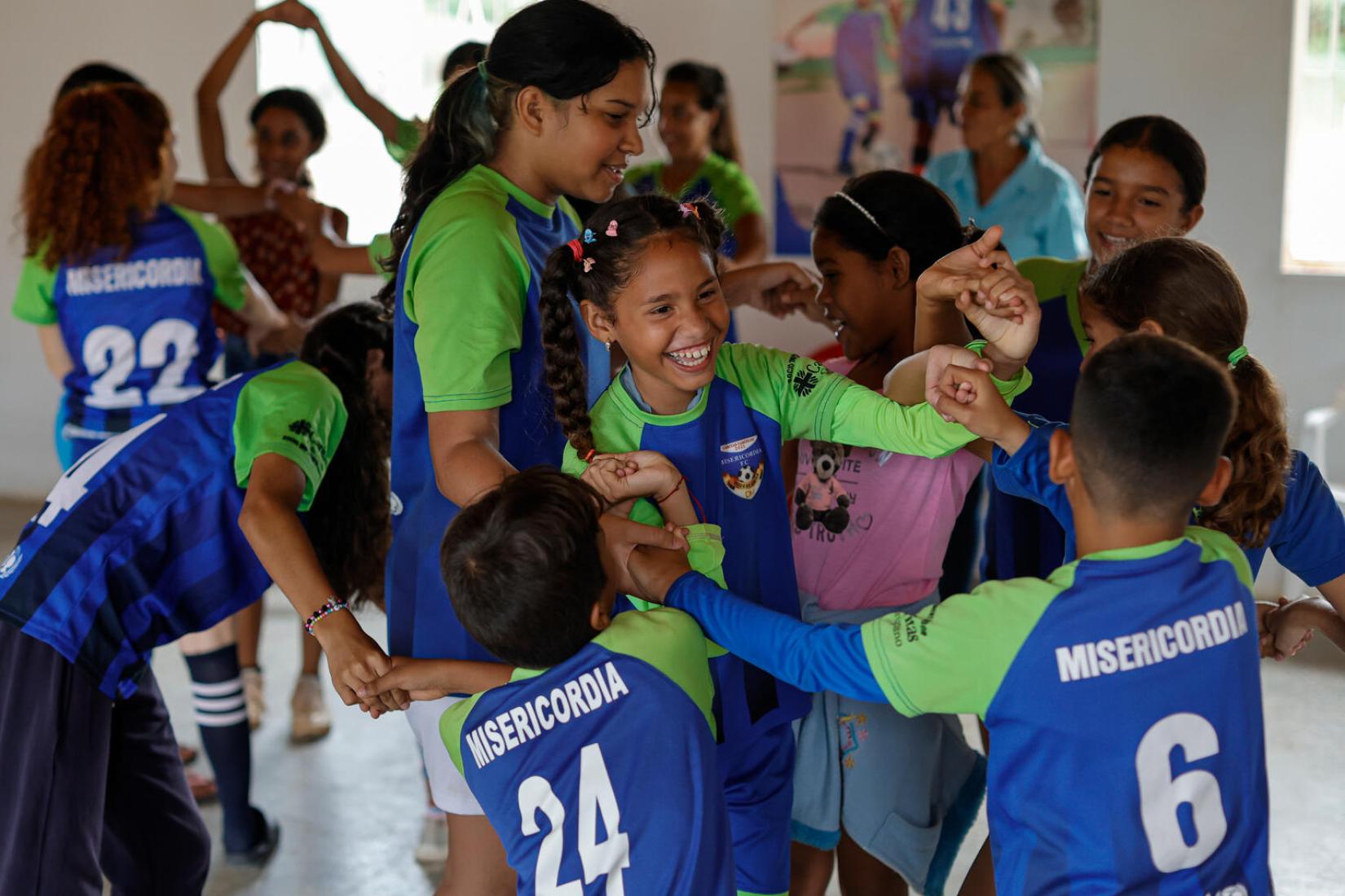 Emmarys Jiménez (cen, izq) participa junto a sus compañeros de la academia Misericordia F.C., durante una sesión de integración grupal llamada Nudo Humano, que promueve la resolución de conflictos en las relaciones humanas.