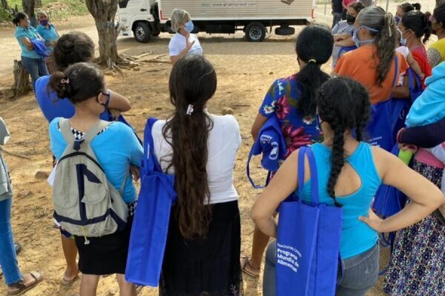 La nutricionista Nora Arroyo (al centro) reúne bajo un árbol a las mujeres que han venido a buscar las raciones escolares para llevar a casa